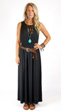 A woman modeling a sleeveless black maxi dress with a brown leather belt featuring silver hardware and a turquoise pendant, styled with layered necklaces and bracelets against a white background.