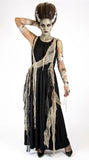 A woman modeling a zombie or mummy Halloween costume against a white studio background. The costume includes a long black dress with tattered beige fabric draped over the shoulders and sides, beige arm wraps, and a large styled brown hairpiece.